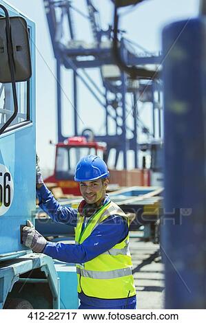 Stock Photo - Worker climbing into truck near cargo crane. Fotosearch