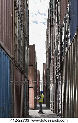 Worker standing between cargo containers View Large Photo Image Stock Image - Worker standing between cargo containers. Fotosearch