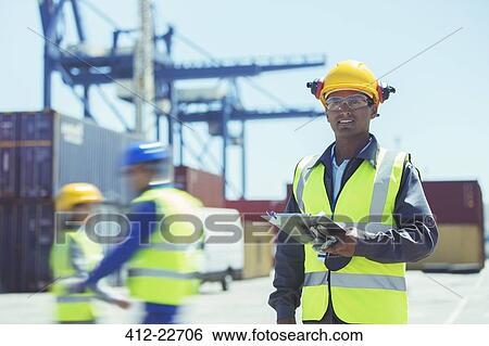 Worker standing near cargo containers View Large Photo Image Stock Photograph - Worker standing near cargo containers. Fotosearch