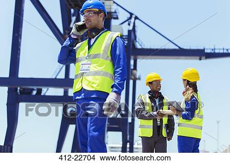 Worker using walkie-talkie near cargo crane View Large Photo Image Picture - Worker using walkie-talkie near cargo crane. Fotosearch