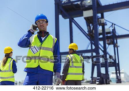 Worker using walkie-talkie near cargo crane View Large Photo Image Stock Photograph - Worker using walkie-talkie near cargo crane. Fotosearch