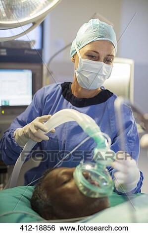 Anesthesiologist holding oxygen mask over patient's face in operating theater View Large Photo Image Stock Photograph - Anesthesiologist holding oxygen mask over patient's face in operating theater. Fotosearch