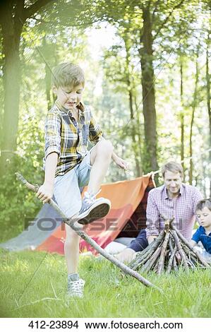 Picture - Boy breaking stick for campfire with father and brother. Fotosearch