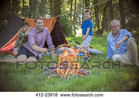 Stock Photo - Boy, father and grandfather relaxing near campfire. Fotosearch