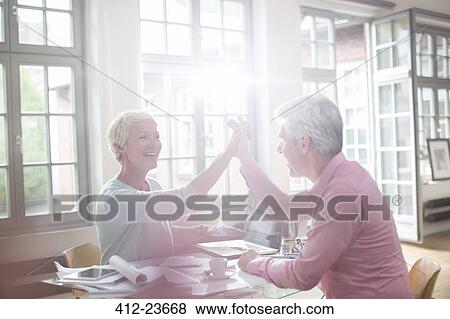 Stock Photo - Business people high fiving at home office desk. Fotosearch