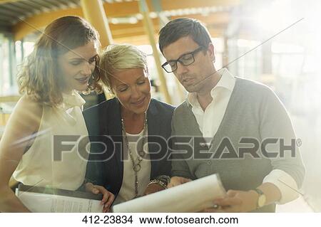 Business people reading paperwork in office View Large Photo Image Picture - Business people reading paperwork in office. Fotosearch