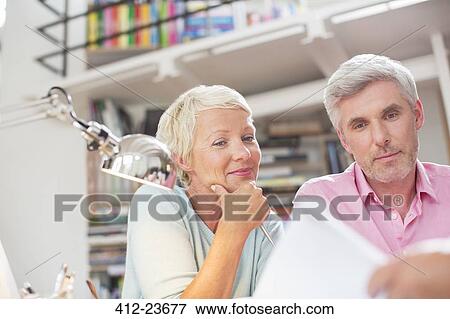 Stock Photo - Business people reading paperwork in office meeting. Fotosearch