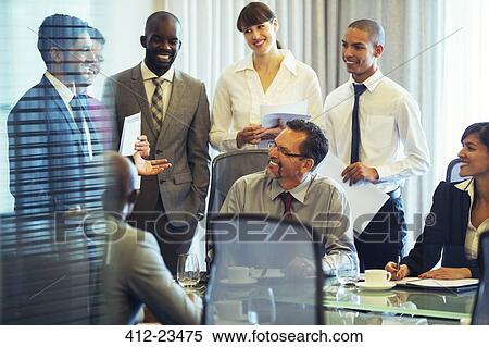 Stock Photography - Business people smiling in conference room during business meeting. Fotosearch