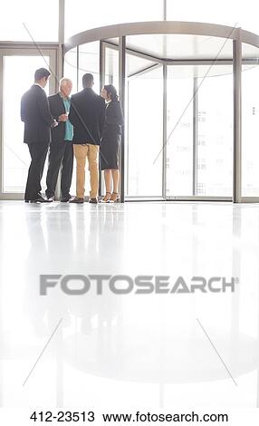 Stock Image - Business people standing and talking near front door of office. Fotosearch