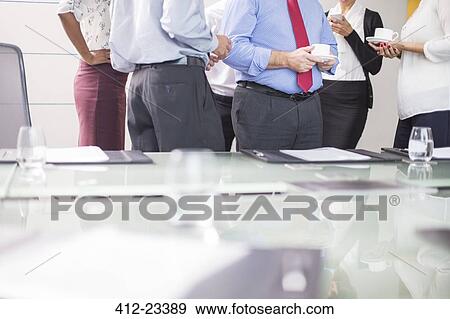 Business people standing in conference room with coffee cups in hands View Large Photo Image Stock Photo - Business people standing in conference room with coffee cups in hands. Fotosearch