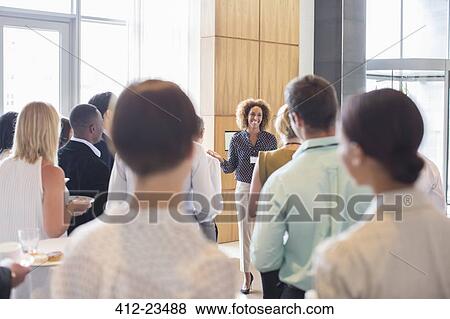 Business people standing in office hall holding trays with cakes and drinking water View Large Photo Image Stock Photo - Business people standing in office hall holding trays with cakes and drinking water. Fotosearch