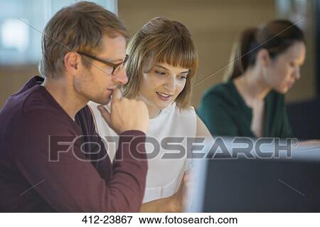 Stock Photo - Business people working late in office. Fotosearch