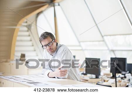 Businessman reading paperwork at office desk View Large Photo Image Stock Photo - Businessman reading paperwork at office desk. Fotosearch