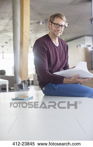 Businessman reading paperwork in office View Large Photo Image Stock Photography - Businessman reading paperwork in office. Fotosearch