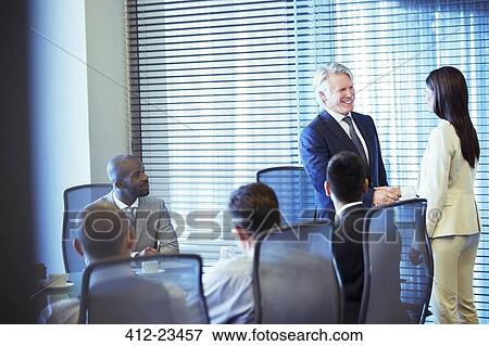 Businessman shaking hands with businesswoman in conference room View Large Photo Image Stock Photo - Businessman shaking hands with businesswoman in conference room. Fotosearch
