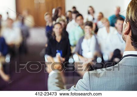 Stock Image - Businessman speaking to audience in conference room. Fotosearch