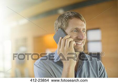 Businessman talking on cell phone in office View Large Photo Image Picture - Businessman talking on cell phone in office. Fotosearch