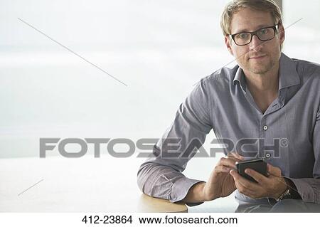 Businessman using cell phone at table View Large Photo Image Picture - Businessman using cell phone at table. Fotosearch