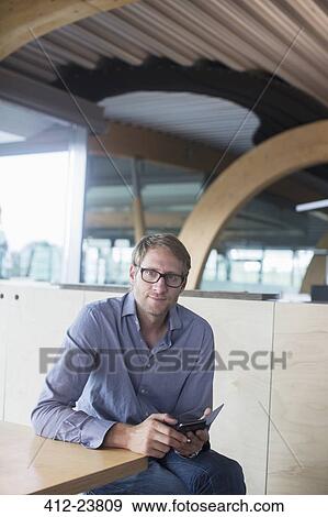 Stock Photo - Businessman using cell phone in office. Fotosearch