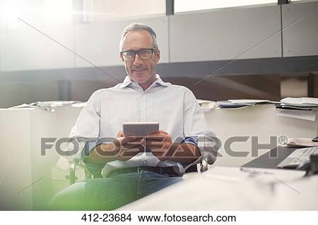 Businessman using digital tablet at office desk View Large Photo Image Picture - Businessman using digital tablet at office desk. Fotosearch