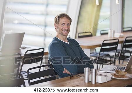 Businessman using laptop in cafeteria View Large Photo Image Stock Photography - Businessman using laptop in cafeteria. Fotosearch
