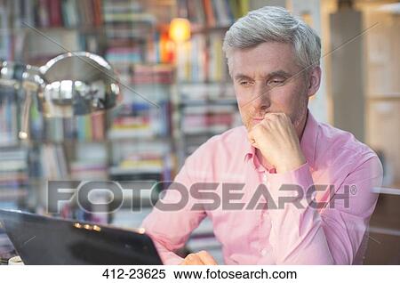Businessman using laptop in home office View Large Photo Image Stock Photography - Businessman using laptop in home office. Fotosearch