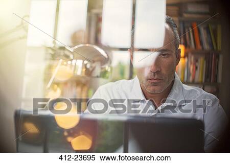 Businessman using laptop in home office View Large Photo Image Stock Photography - Businessman using laptop in home office. Fotosearch