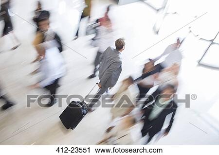Businessman walking through lobby of public building towards exit, wheeling trolley case View Large Photo Image Stock Image - Businessman walking through lobby of public building towards exit, wheeling trolley case. Fotosearch