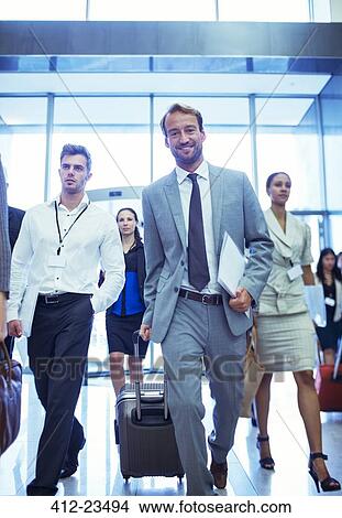 Businessman with suitcase and documents walking in office View Large Photo Image Picture - Businessman with suitcase and documents walking in office. Fotosearch