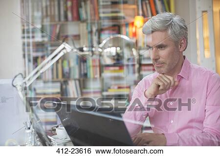 Businessman working on laptop in home office View Large Photo Image Stock Photograph - Businessman working on laptop in home office. Fotosearch
