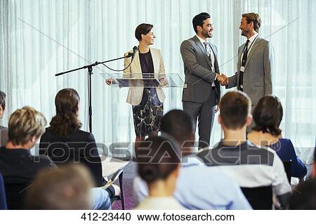 Businessmen shaking hands during presentation in conference room, businesswoman smiling View Large Photo Image Stock Image - Businessmen shaking hands during presentation in conference room, businesswoman smiling. Fotosearch