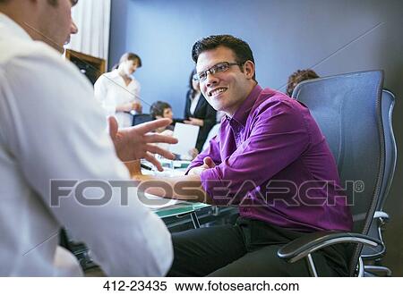 Businessmen talking during meeting in conference room with colleagues in background View Large Photo Image Stock Photography - Businessmen talking during meeting in conference room with colleagues in background. Fotosearch
