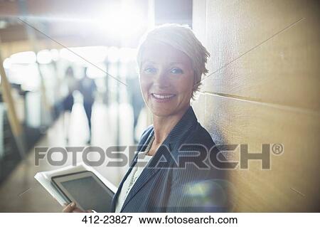 Businesswoman carrying digital tablet in office View Large Photo Image Stock Photo - Businesswoman carrying digital tablet in office. Fotosearch