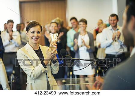 Stock Photo - Businesswoman giving award to businessman, colleagues in background. Fotosearch