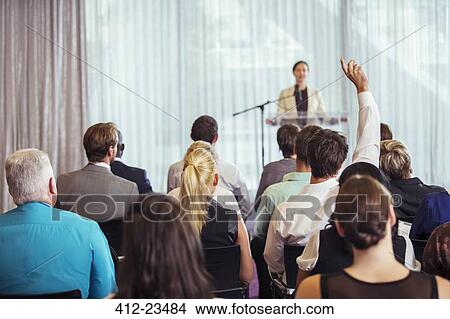 Businesswoman giving presentation in conference room, people raising hands View Large Photo Image Picture - Businesswoman giving presentation in conference room, people raising hands. Fotosearch