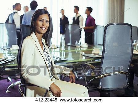 Businesswoman posing in conference room, colleagues standing background View Large Photo Image Stock Photography - Businesswoman posing in conference room, colleagues standing background. Fotosearch