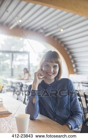 Stock Image - Businesswoman sitting at table in cafeteria. Fotosearch