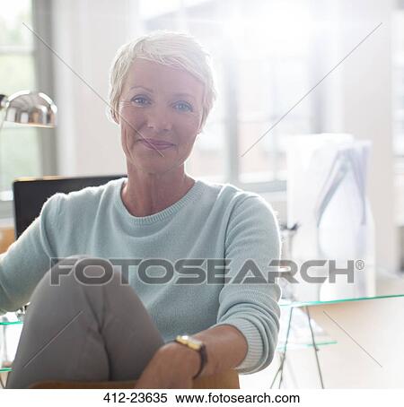 Stock Photography - Businesswoman smiling at desk. Fotosearch