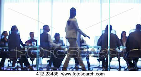 Businesswoman walking in front of colleagues during business meeting in conference room View Large Photo Image Stock Photo - Businesswoman walking in front of colleagues during business meeting in conference room. Fotosearch