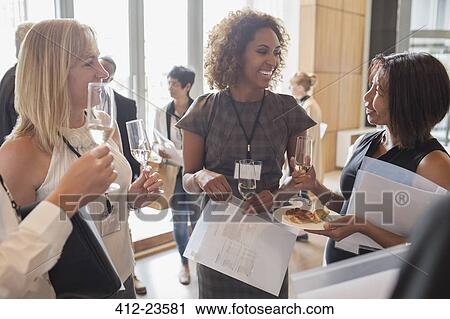Businesswomen holding flutes of champagne and documents during meeting break View Large Photo Image Stock Image - Businesswomen holding flutes of champagne and documents during meeting break. Fotosearch