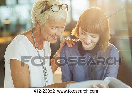 Stock Image - Businesswomen reading paperwork in office. Fotosearch