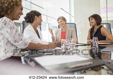 Businesswomen sitting at conference table talking View Large Photo Image Picture - Businesswomen sitting at conference table talking. Fotosearch