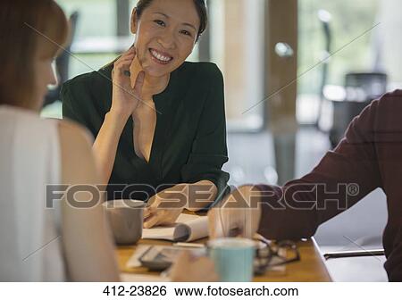 Stock Photograph - Businesswomen smiling in office meeting. Fotosearch