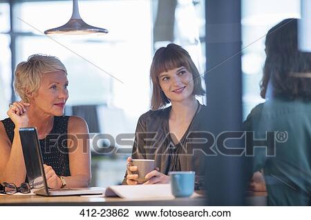 Stock Image - Businesswomen talking in office meeting. Fotosearch