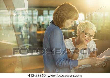 Stock Image - Businesswomen working together in office. Fotosearch
