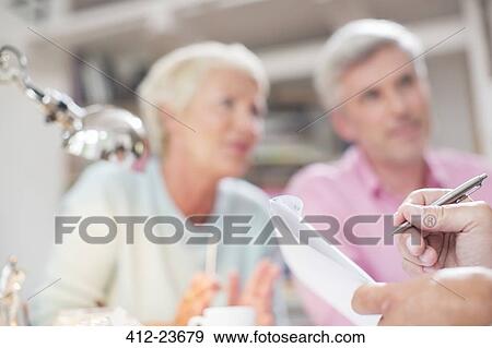 Stock Photo - Close up of businessman writing on notepad in meeting. Fotosearch