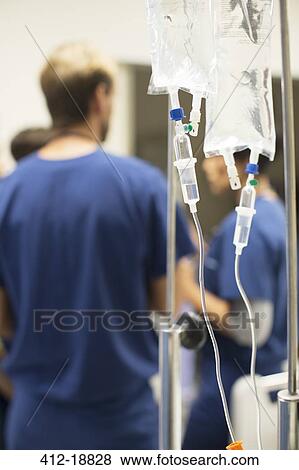 Close up of IV drip bags, doctors in background View Large Photo Image Stock Photo - Close up of IV drip bags, doctors in background. Fotosearch
