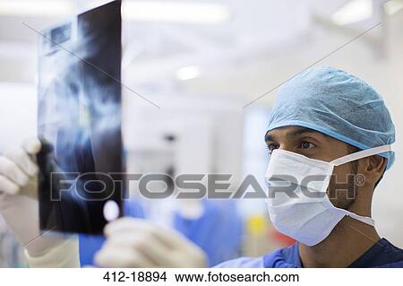 Close up of surgeon wearing surgical cap and mask looking at x-ray in operating theater View Large Photo Image Picture - Close up of surgeon wearing surgical cap and mask looking at x-ray in operating theater. Fotosearch
