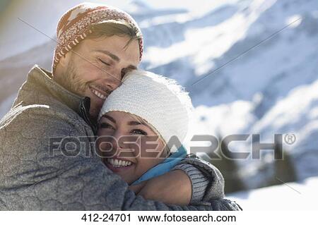 Stock Image - Couple hugging in snow. Fotosearch