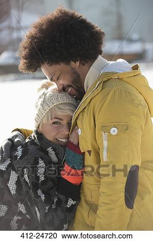 Stock Image - Couple hugging in snow. Fotosearch